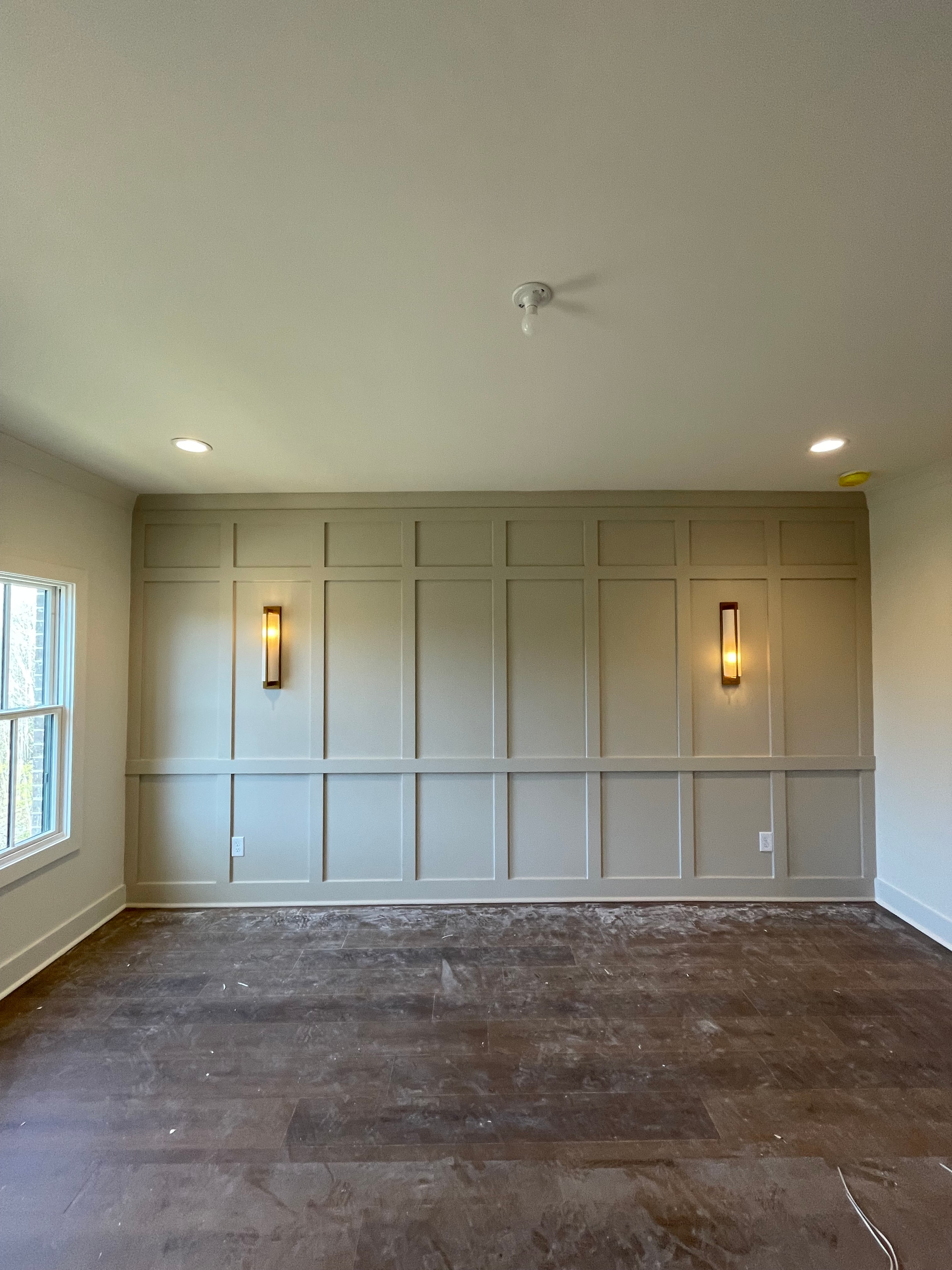 Taupe paneled accent wall with sconce lighting